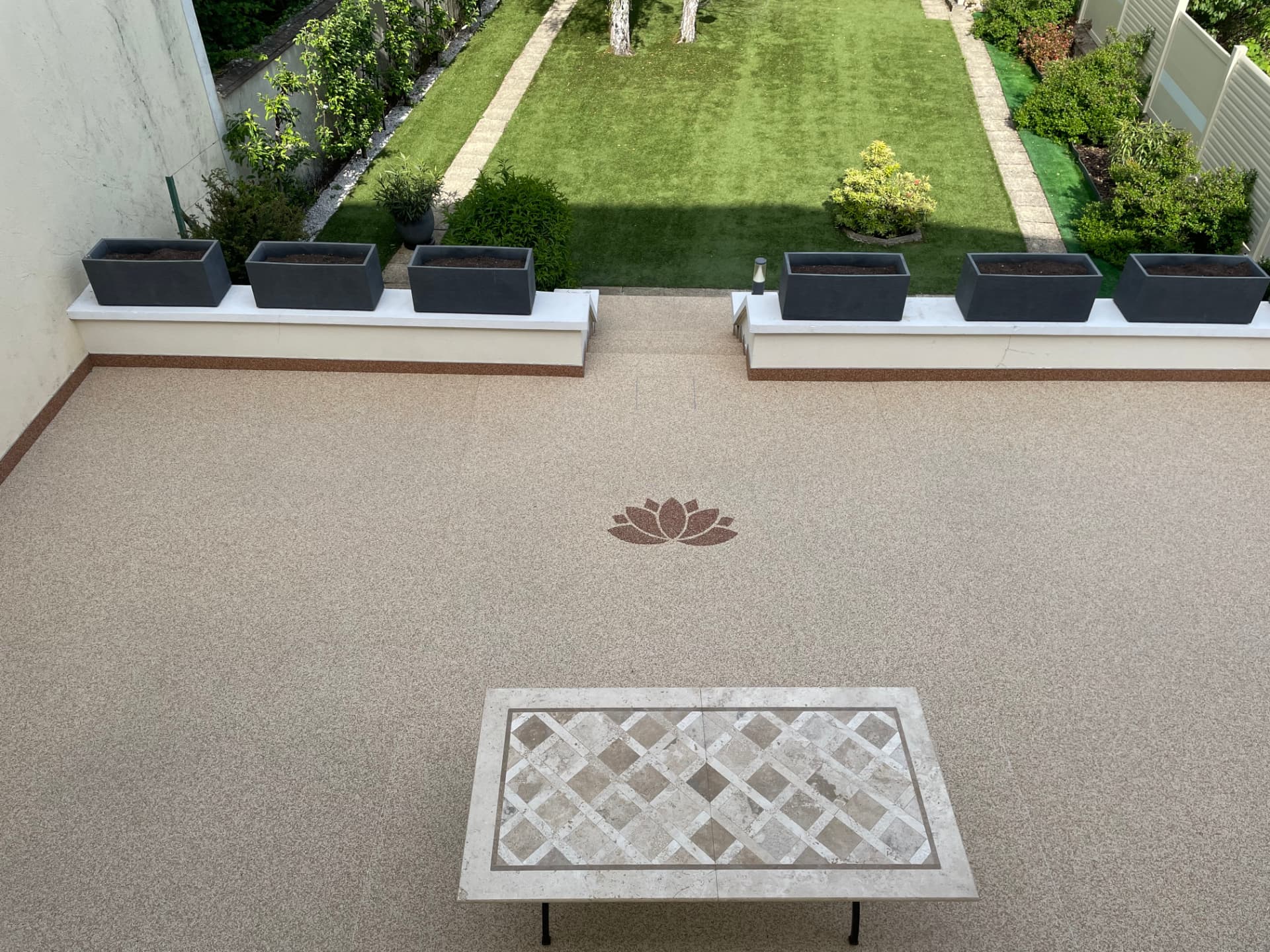 Terrasse en moquette de pierre avec motif lotus donnant sur le jardin