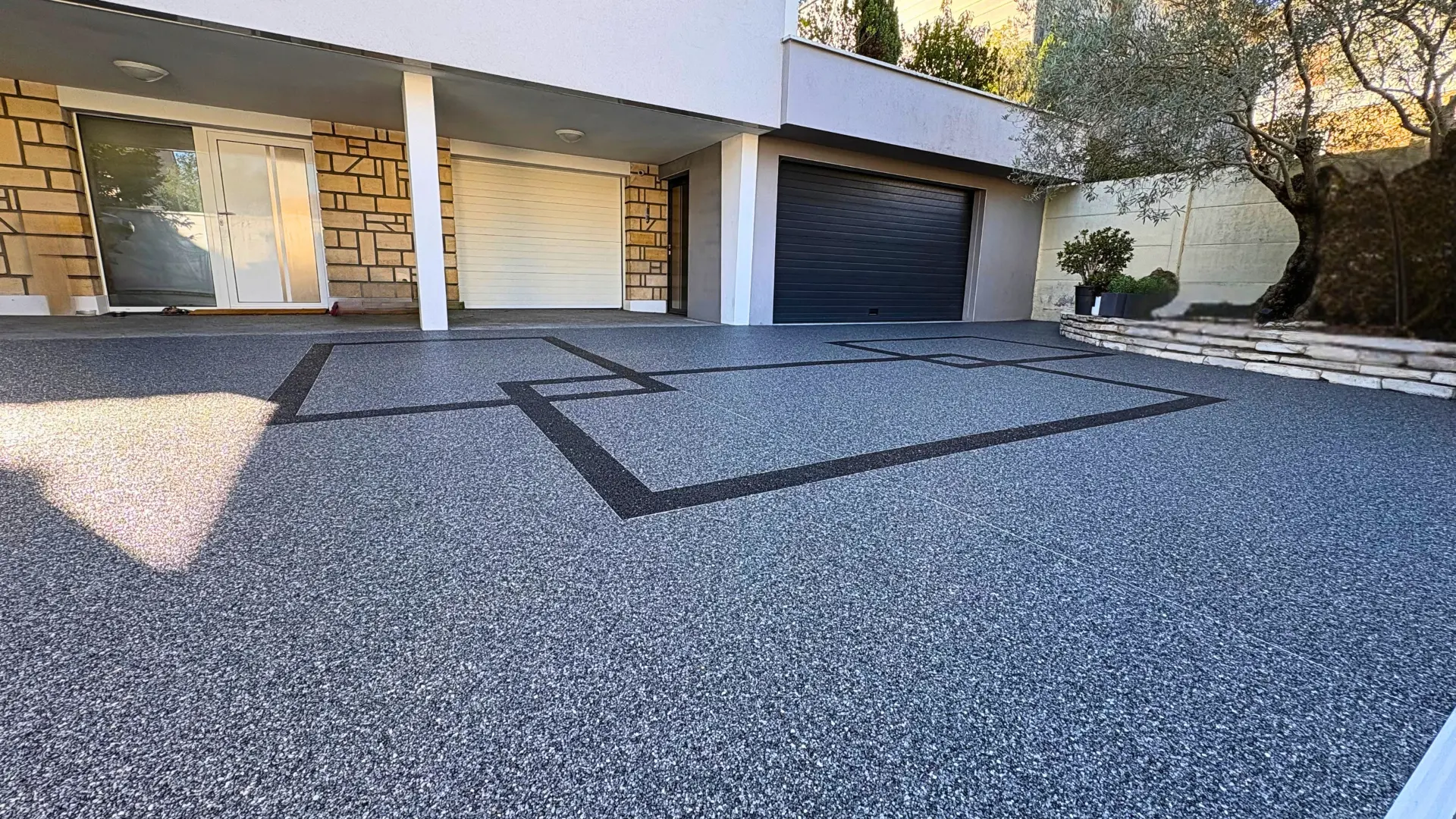 Cour et entrée en moquette de pierre avec motifs géométriques devant un garage en Essonne